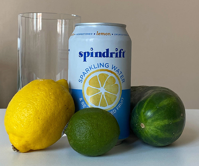 Lemon, limes, soda water can and clear glass on table