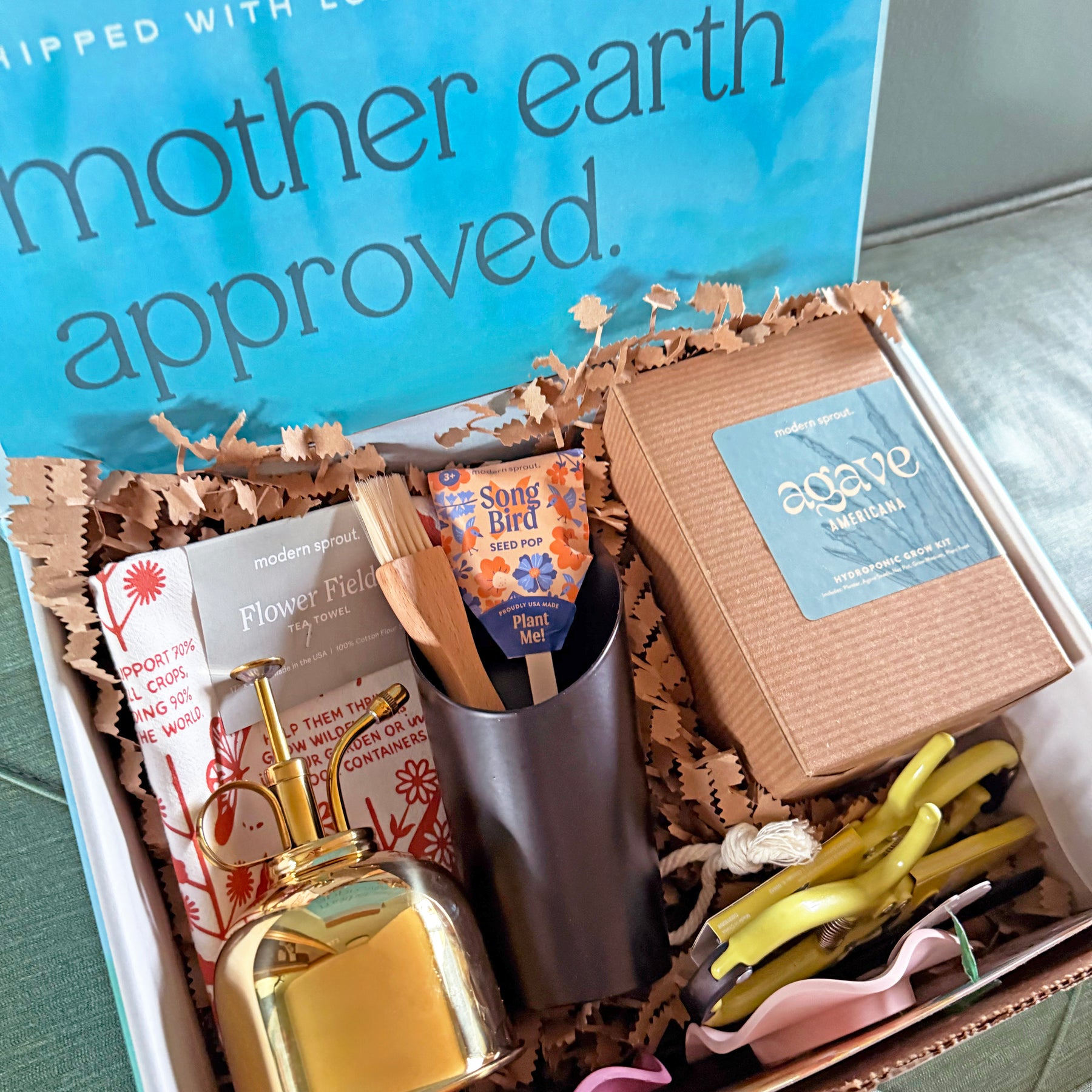 Limited edition gift box featuring plant care items, including a watering can, seed packets, and a decorative bell.
