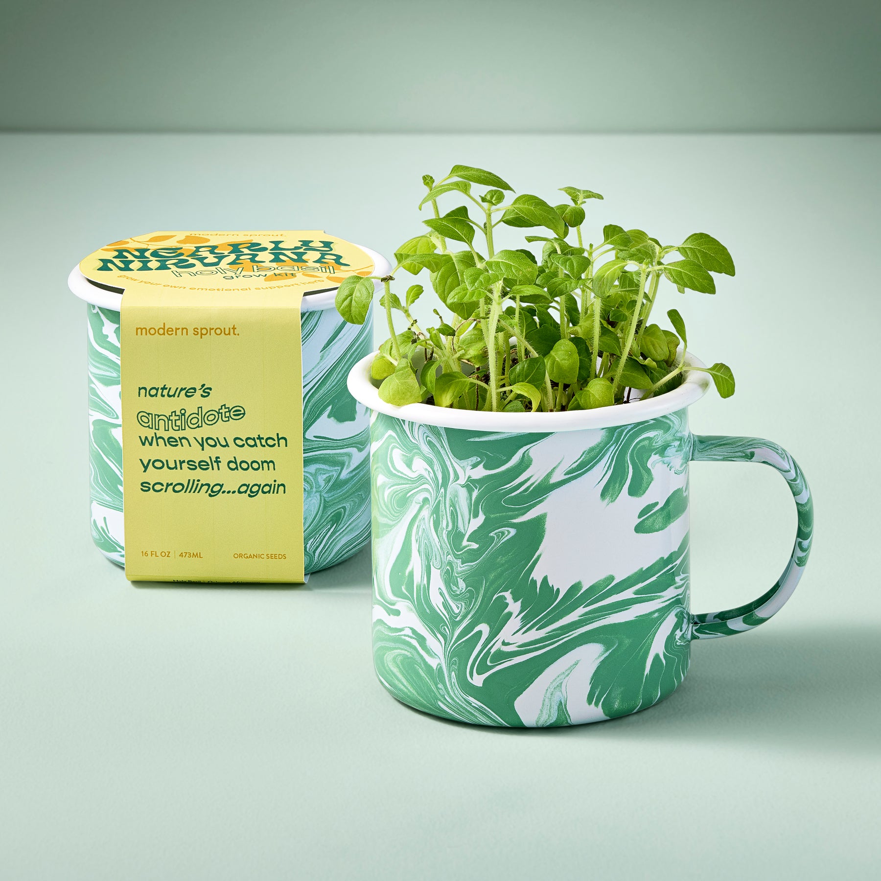 Marbled green mug with growing herbs, accompanied by a yellow packaging label, set against a soft green background.