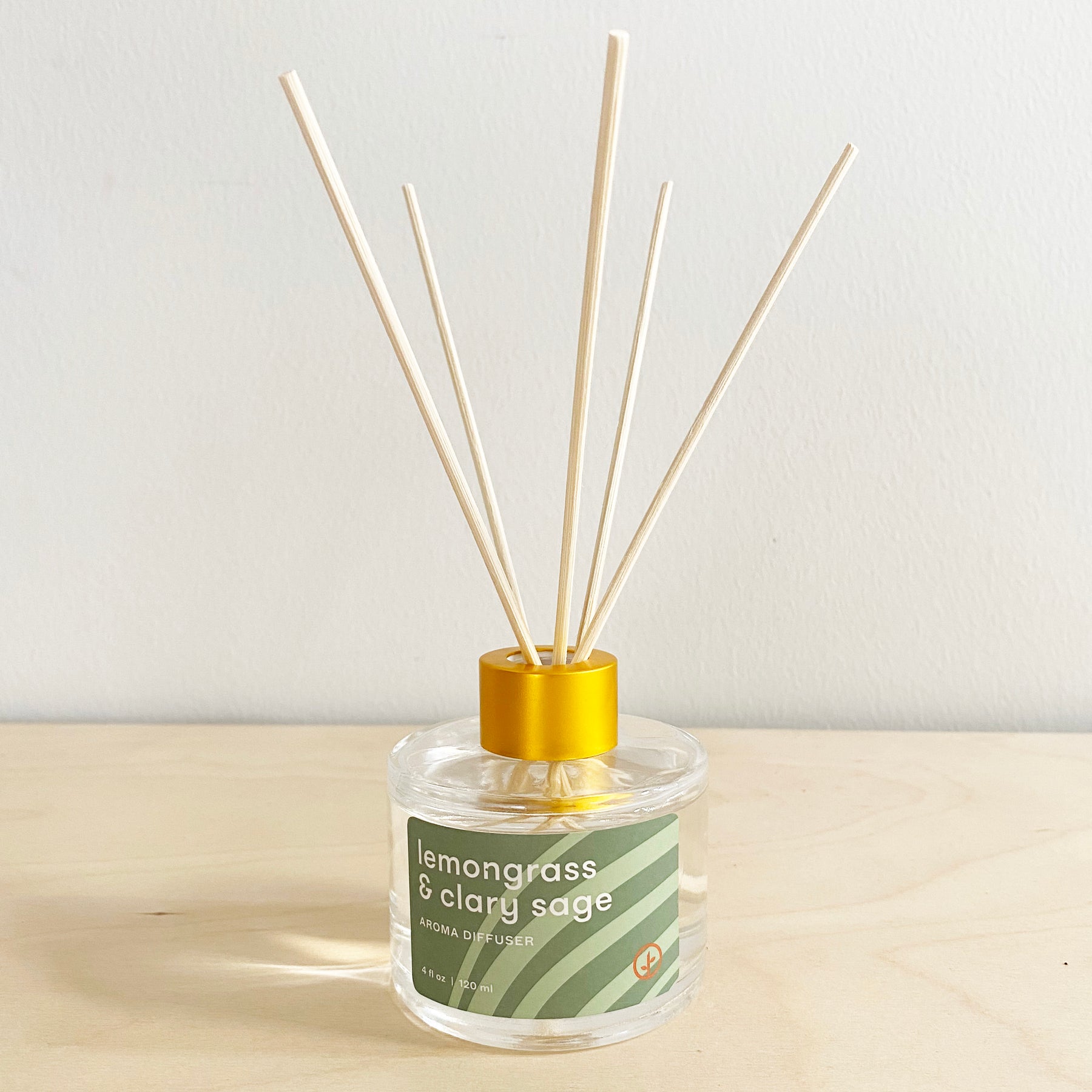 Aroma diffuser with lemongrass and clary sage scent, featuring wooden reeds in a clear glass bottle with a yellow cap.
