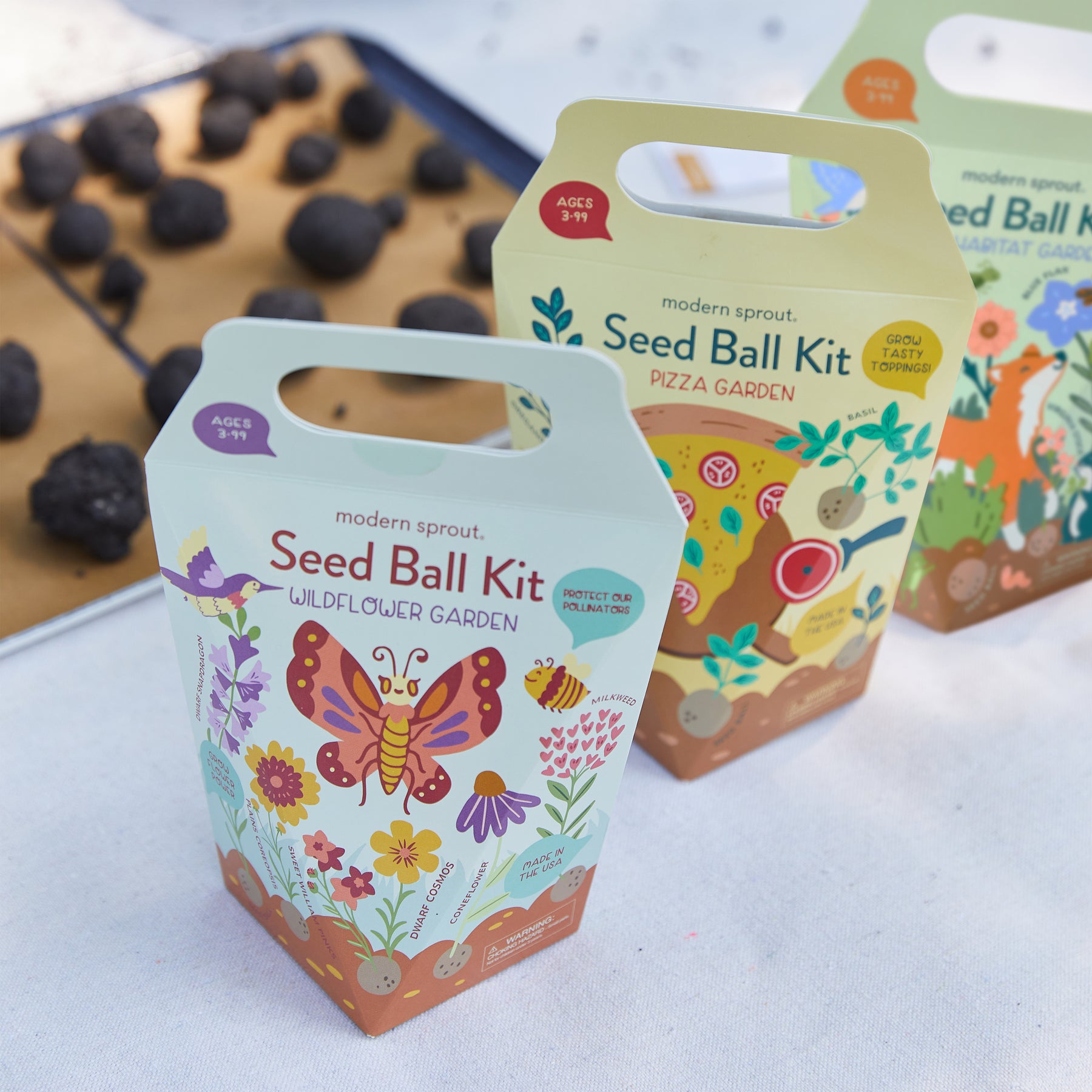 Colorful seed ball kits for wildflower and pizza gardens, featuring illustrated designs and easy-to-carry packaging.