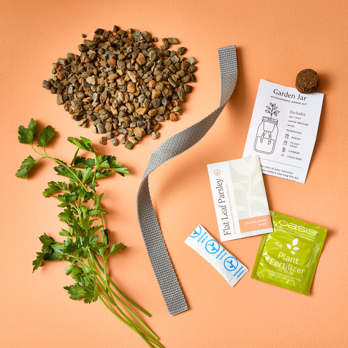 Passive Hydroponic Replant Kit components including gravel, plant fertilizer, seeds, and a growing guide on an orange background.