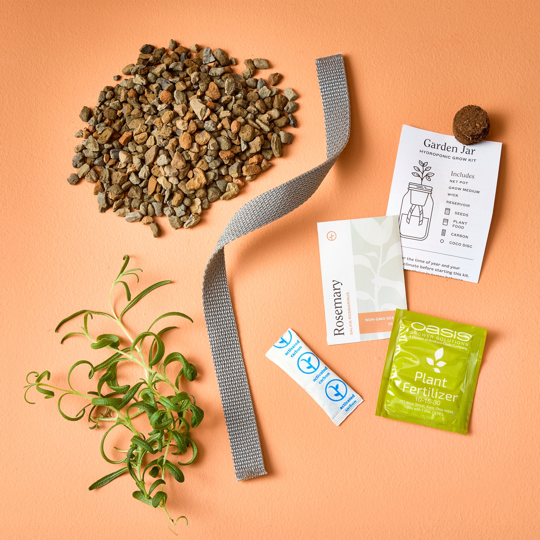 Passive Hydroponic Replant Kit featuring gravel, a plant label, fertilizer, and a rosemary cutting on a peach background.