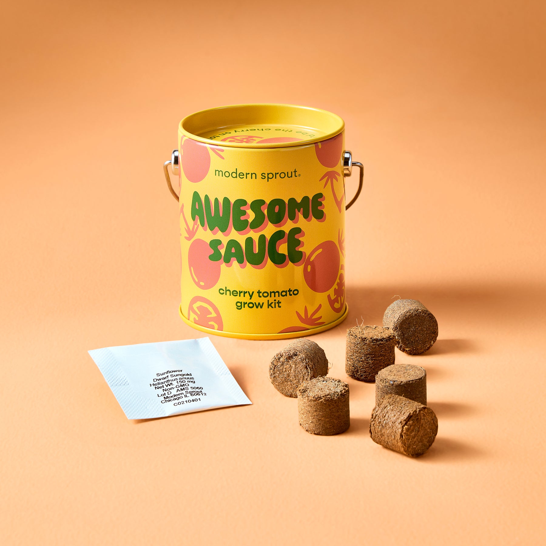 Bright yellow canister labeled "Awesome Sauce" with cherry tomato grow kit, surrounded by soil pellets and a seed packet.