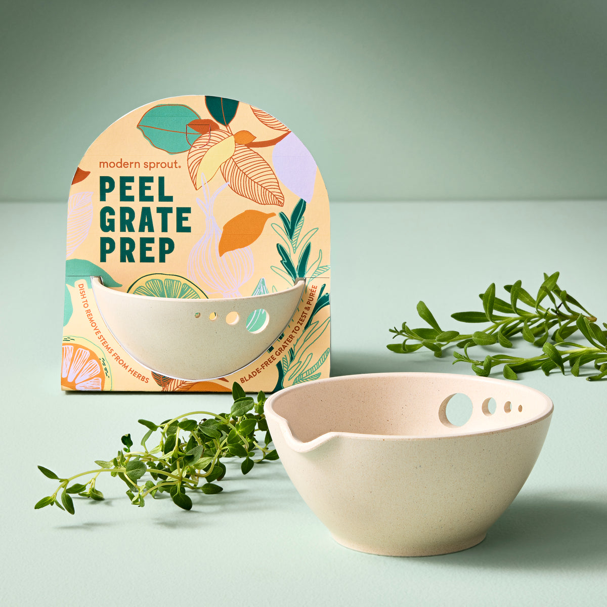Peel, Grate & Prep Dish by Modern Sprout, featuring a textured bowl with holes for easy peeling and grating, surrounded by herbs.