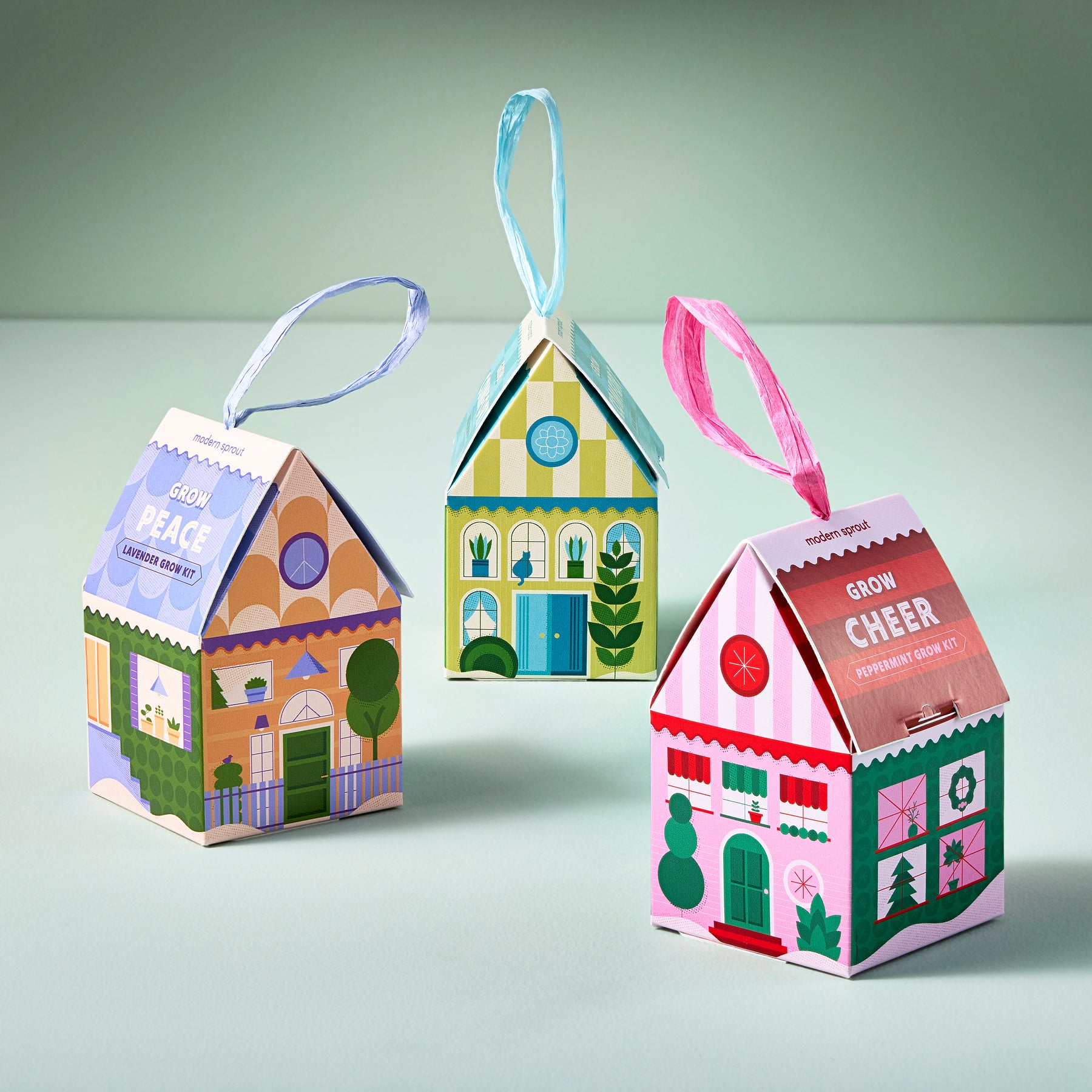 Colorful home-shaped ornaments designed for indoor gardening, featuring cheerful designs and festive messages.