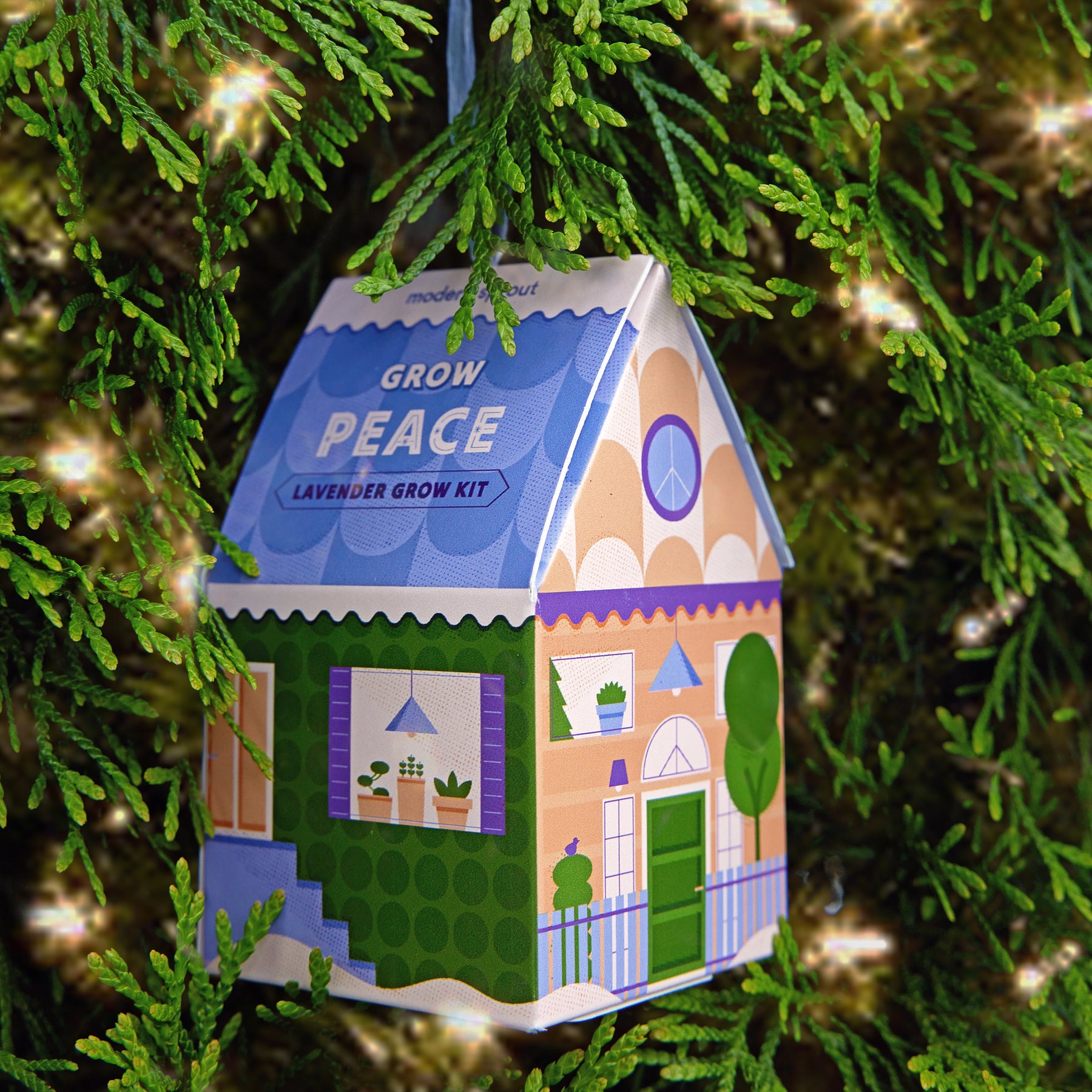 Colorful lavender grow kit ornament shaped like a house, hanging on a green tree branch, promoting indoor gardening.