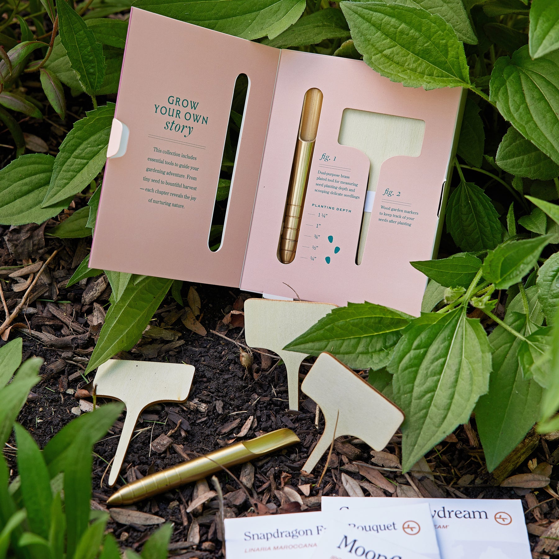 Seed library kit featuring planting instructions, markers, and a gold pen, surrounded by green foliage.