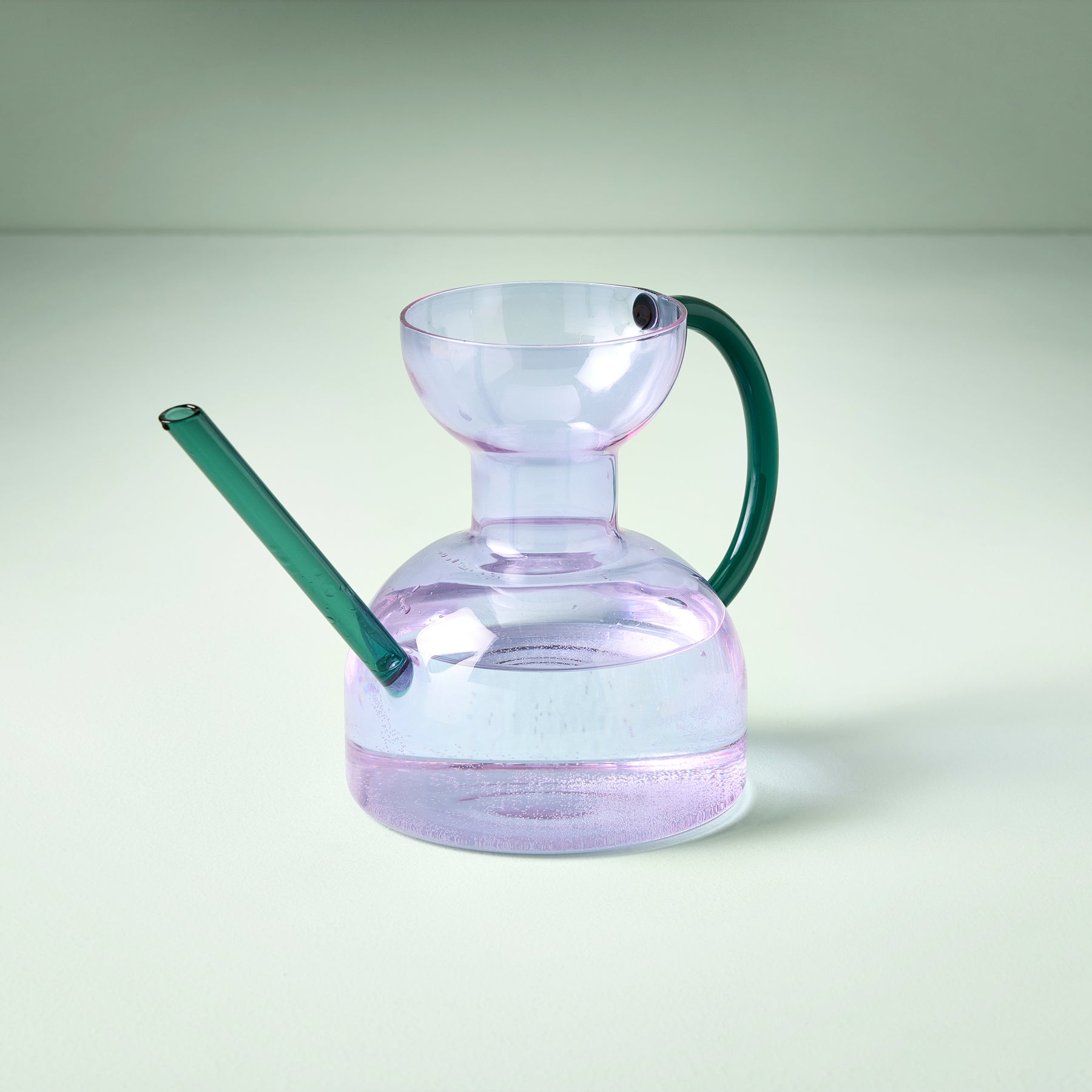 Elegant glass watering can with a purple body and green handle, designed for stylish indoor plant care.