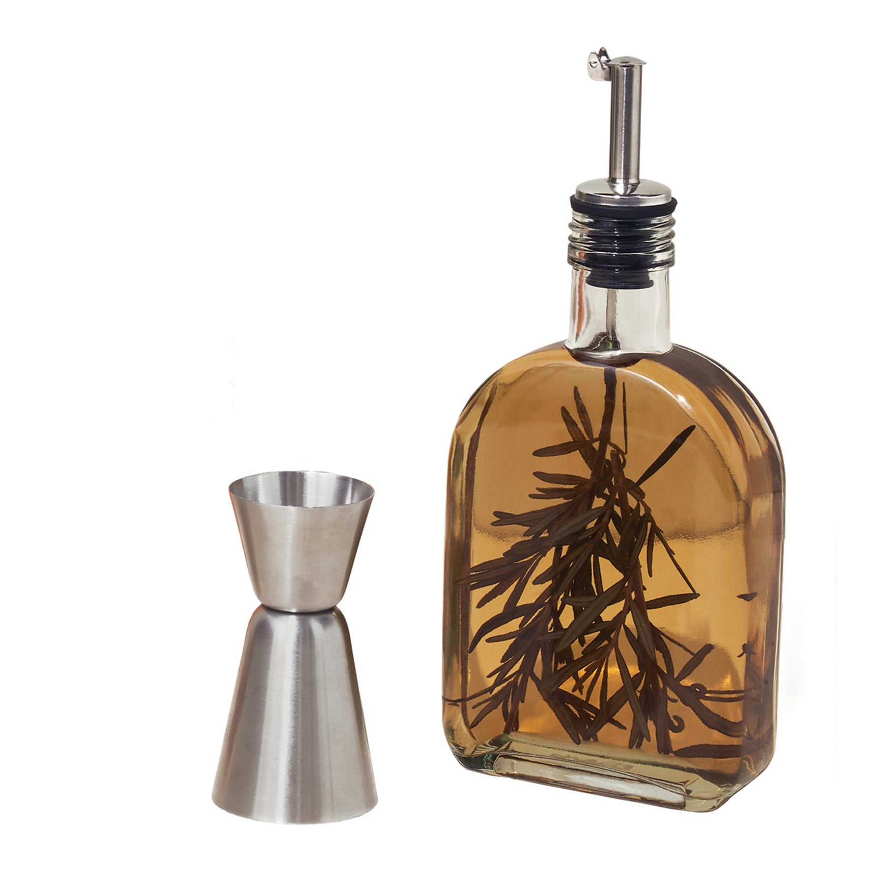 Glass infusion flask filled with infused oil and a stainless steel jigger beside it, showcasing herbs inside the flask.