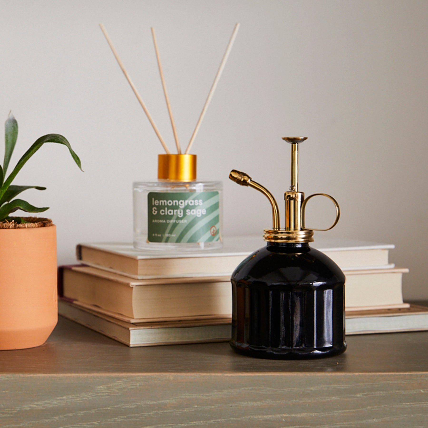Aroma diffuser trio displayed with a plant and a candle, showcasing elegant design and calming scents.