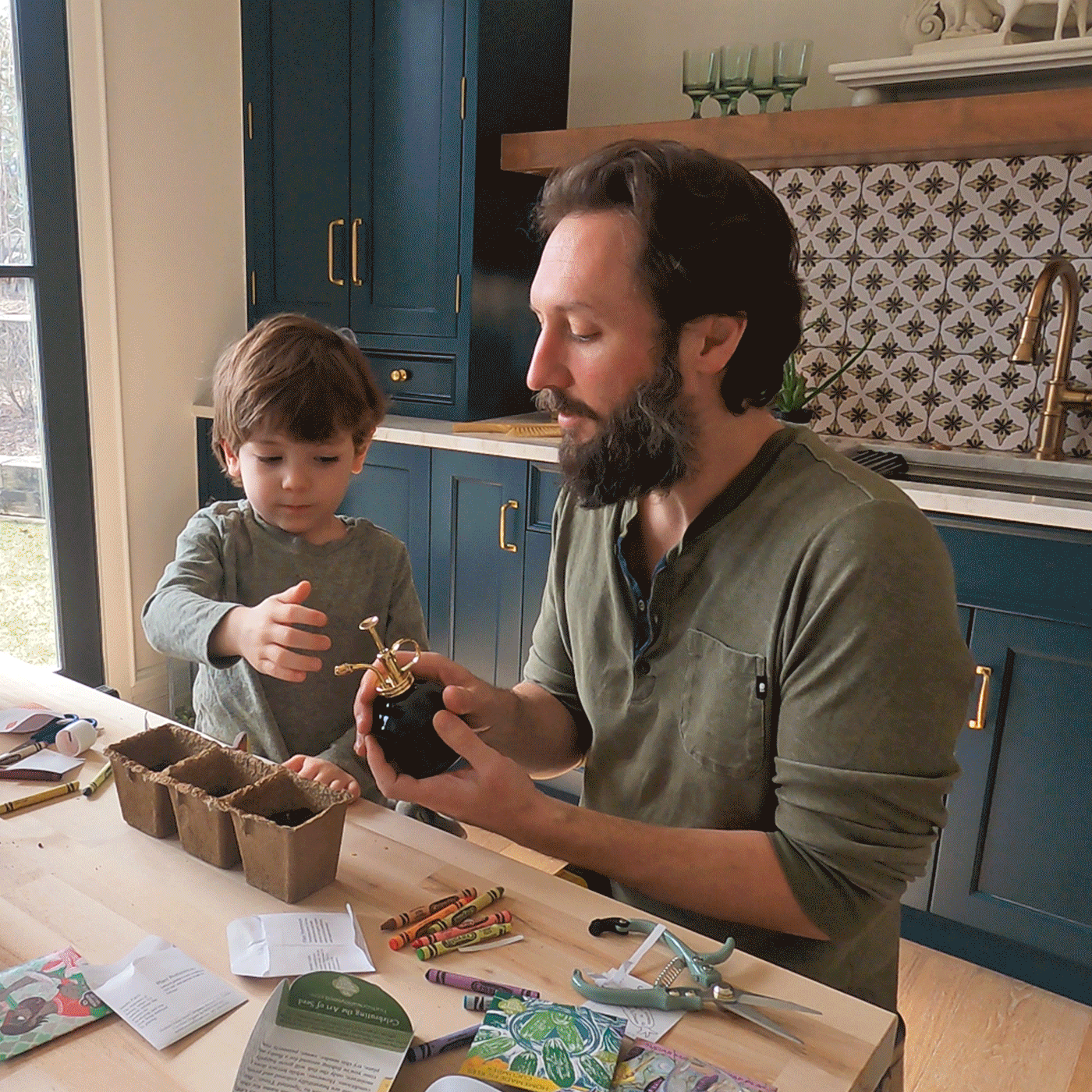 A man and child explore a hydroponic growing kit, surrounded by seedlings, plant accessories, and gardening instructions.