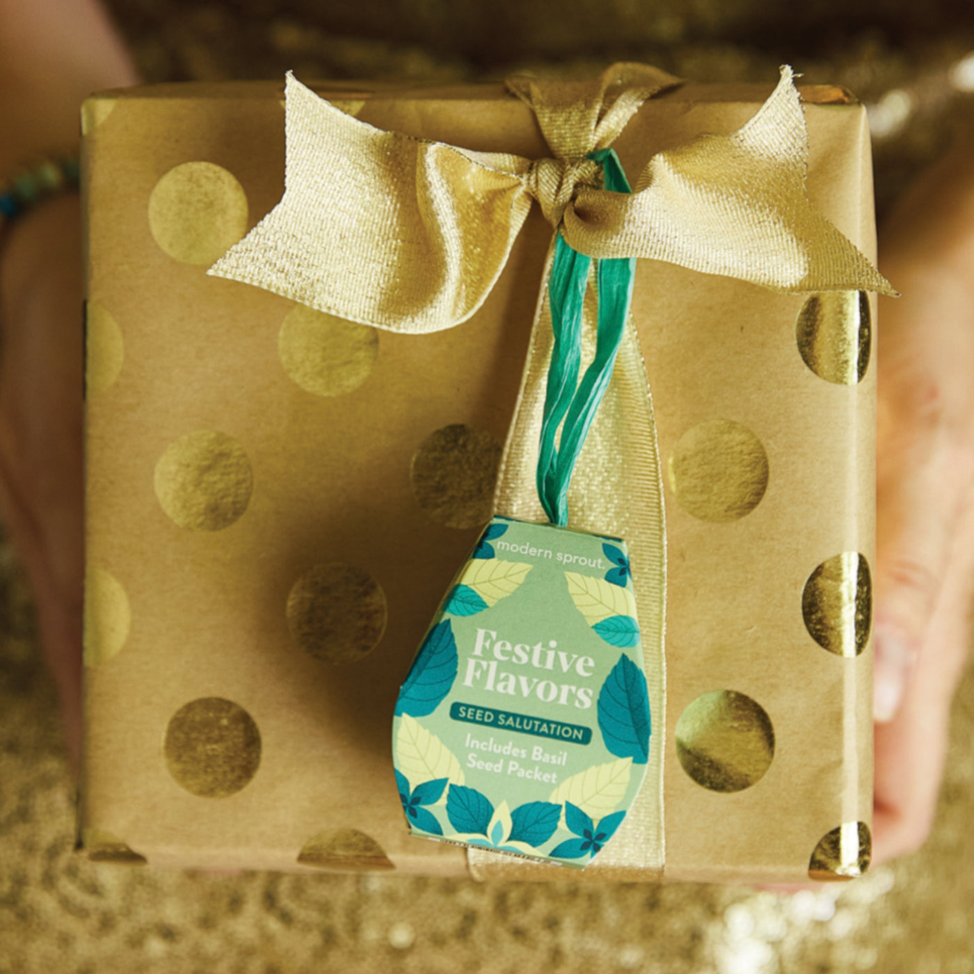 Gold gift box with polka dots, tied with a gold ribbon and green and gold accents, featuring a basil seed packet label.