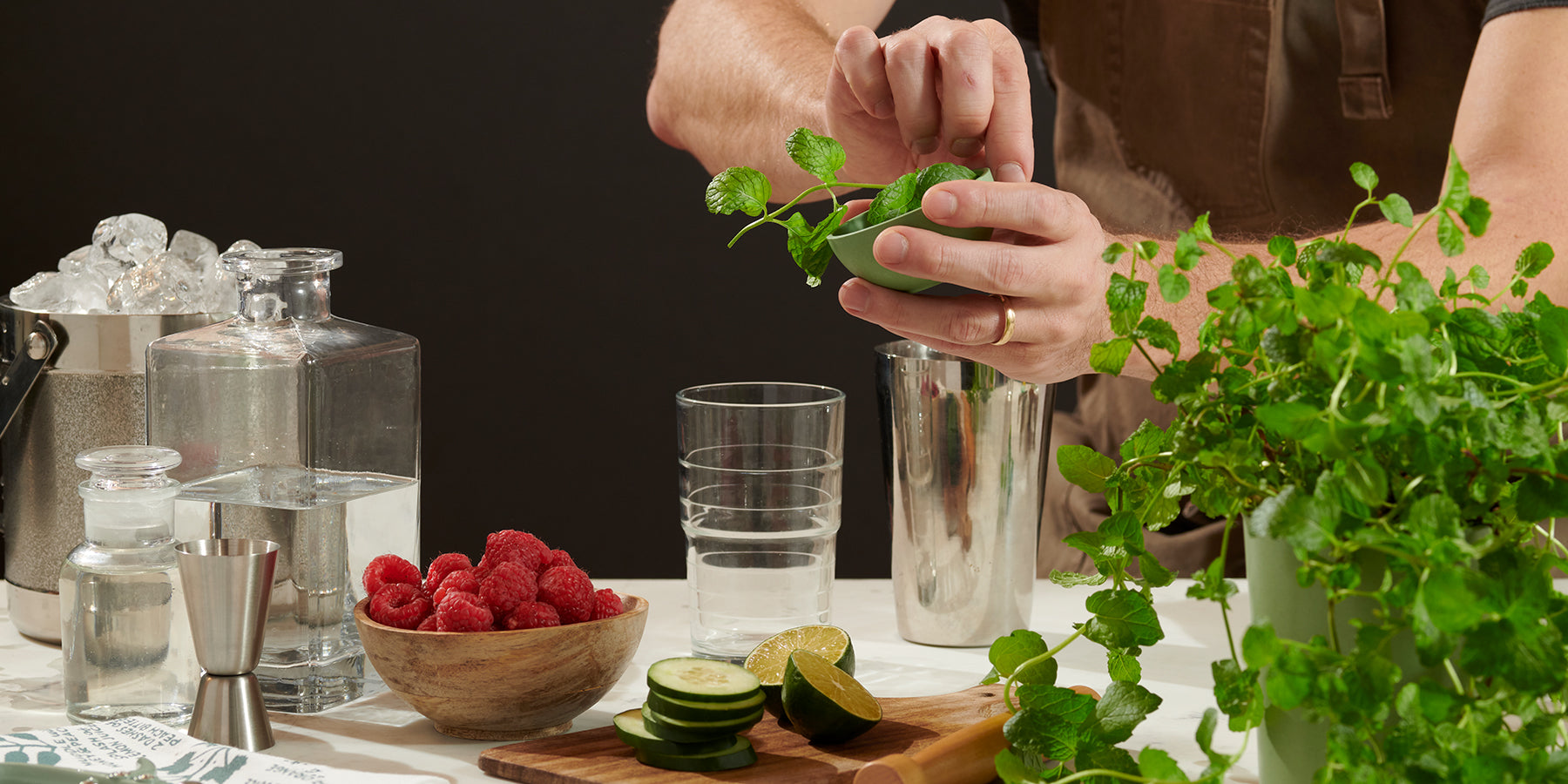 Indoor hydroponic garden kit with lush green herbs, surrounded by fresh fruits and gardening tools on a white table.