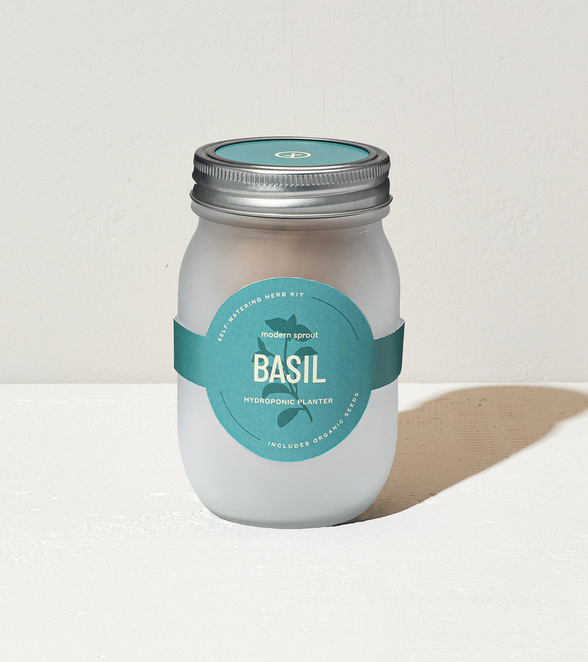 Frosted glass jar labeled "Basil" with a teal band, designed for hydroponic herb planting.