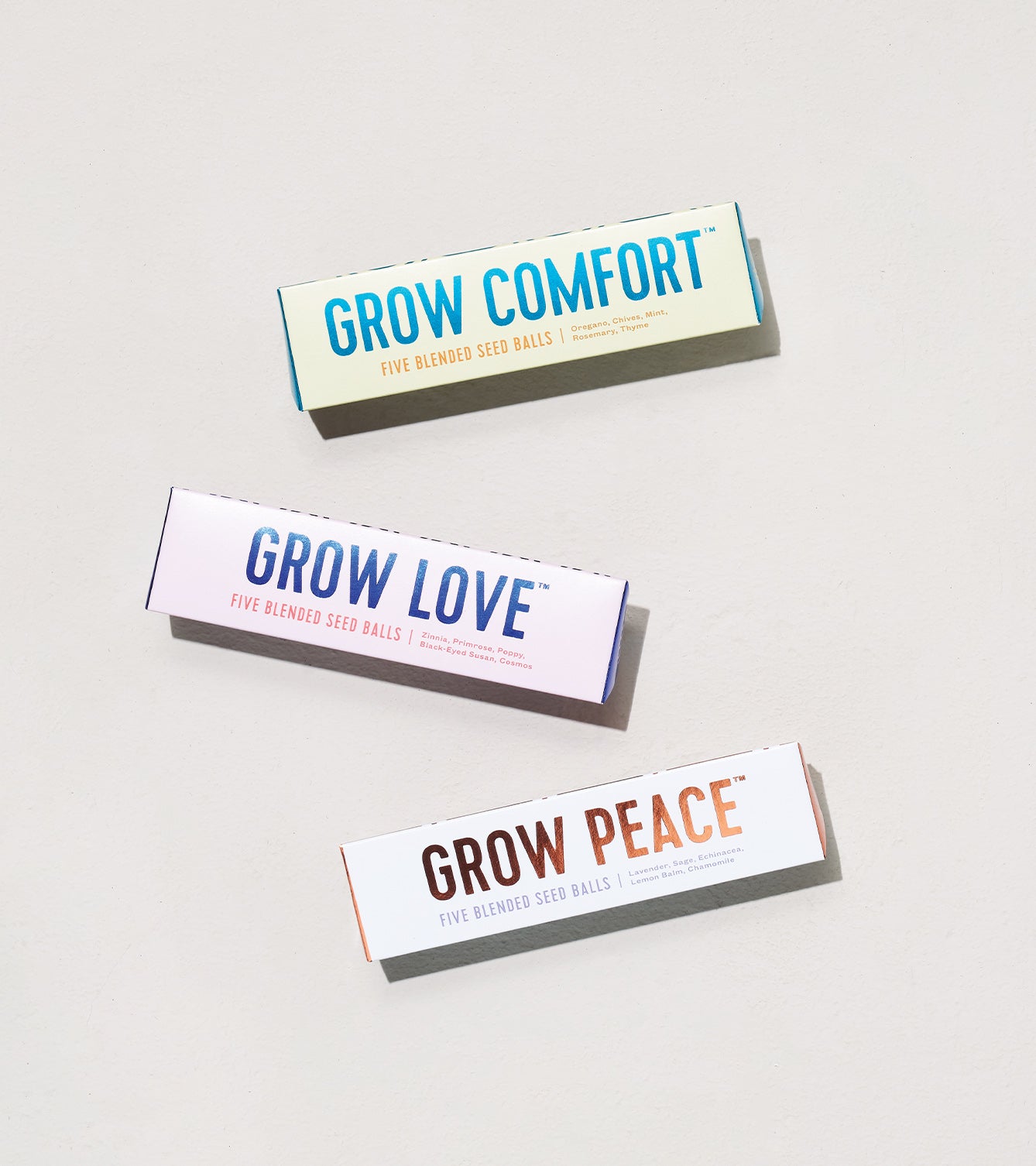 Three colorful boxes of Bright Side Seed Balls labeled Grow Comfort, Grow Love, and Grow Peace, each containing five blended seed balls.