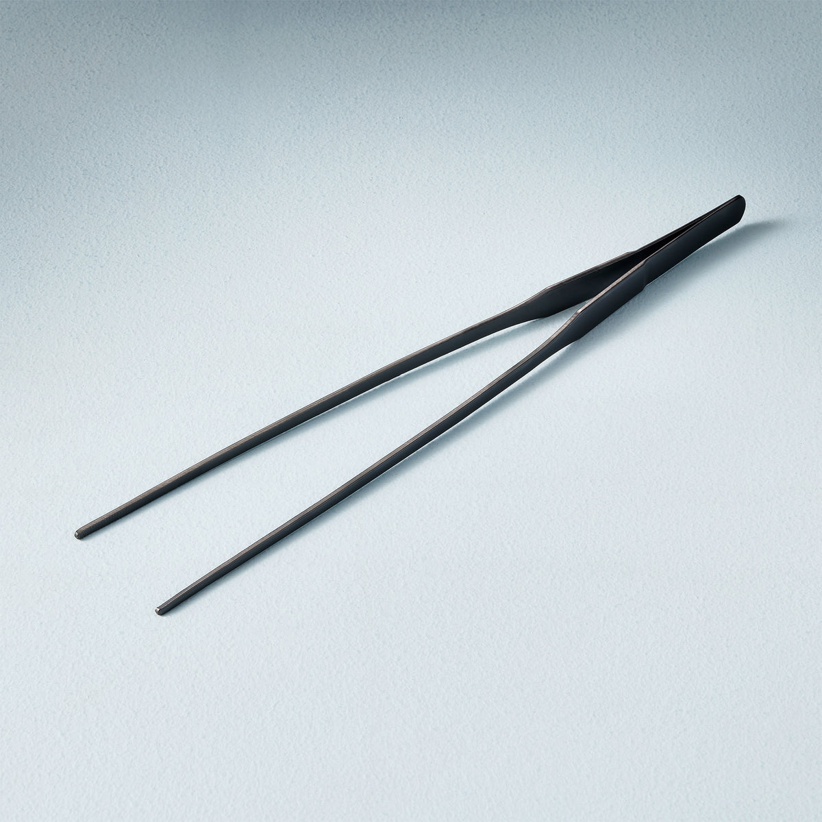 Black plant care tweezers designed for precise handling of small plants and delicate soil adjustments.