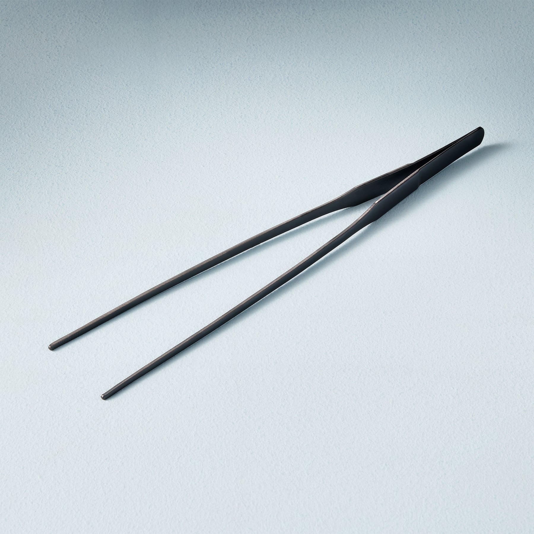 Black plant care tweezers designed for precise handling of small plants and delicate soil adjustments.