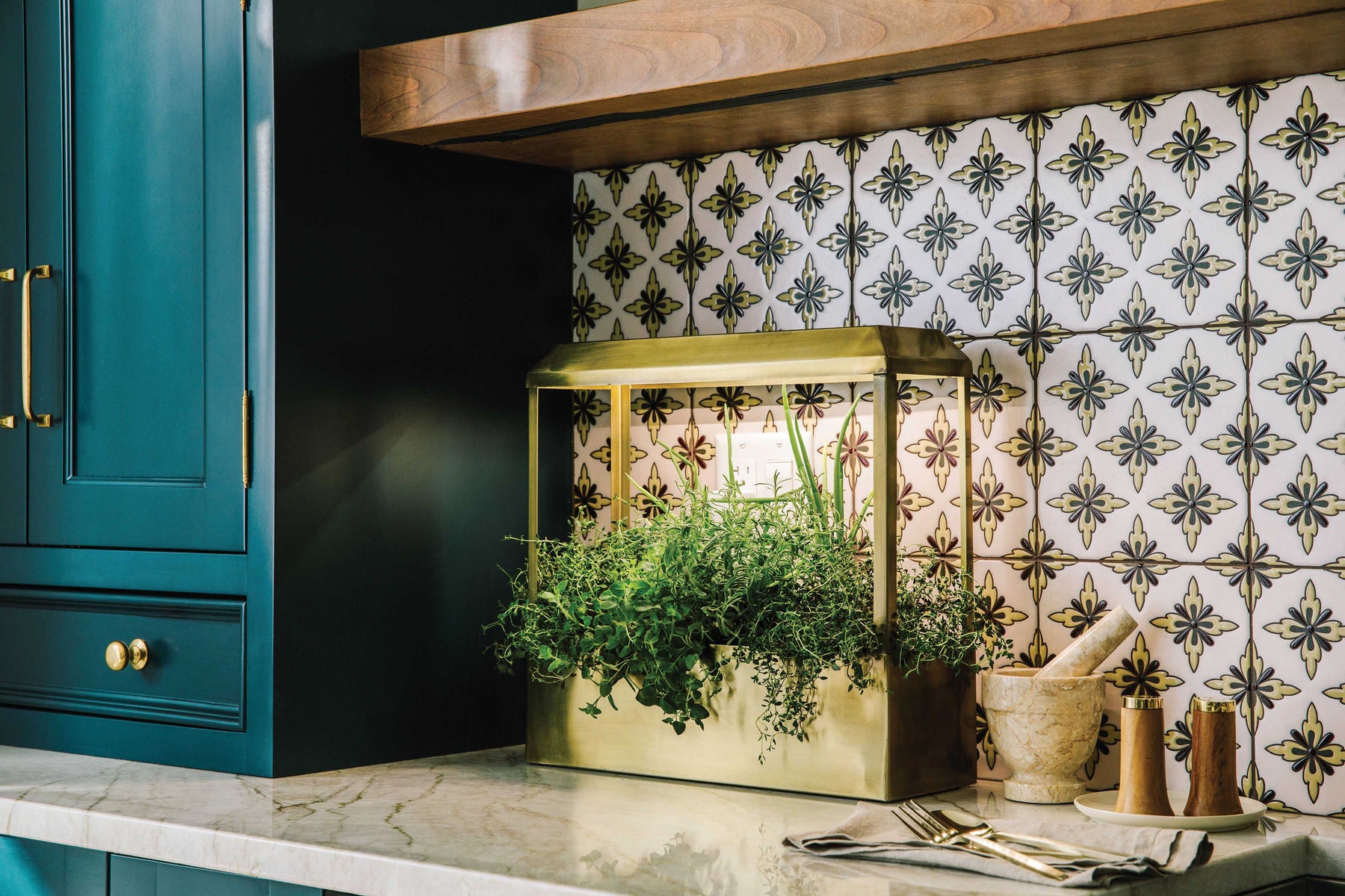 Smart Growhouse with brass frame and lush greenery, displayed on a marble countertop against a patterned tile backsplash.