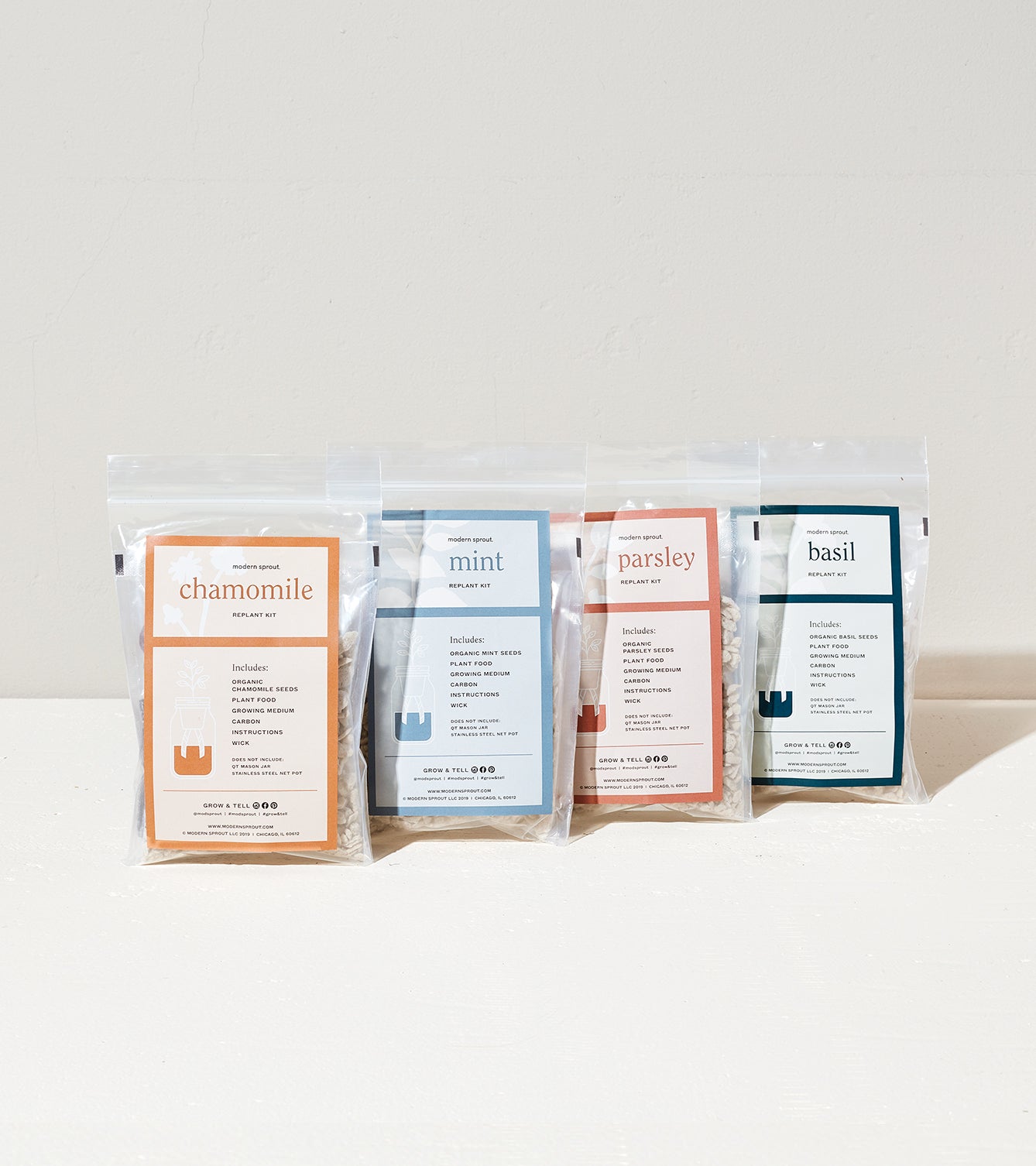 Four packets of herb seeds for chamomile, mint, parsley, and basil, each labeled with planting instructions and details.