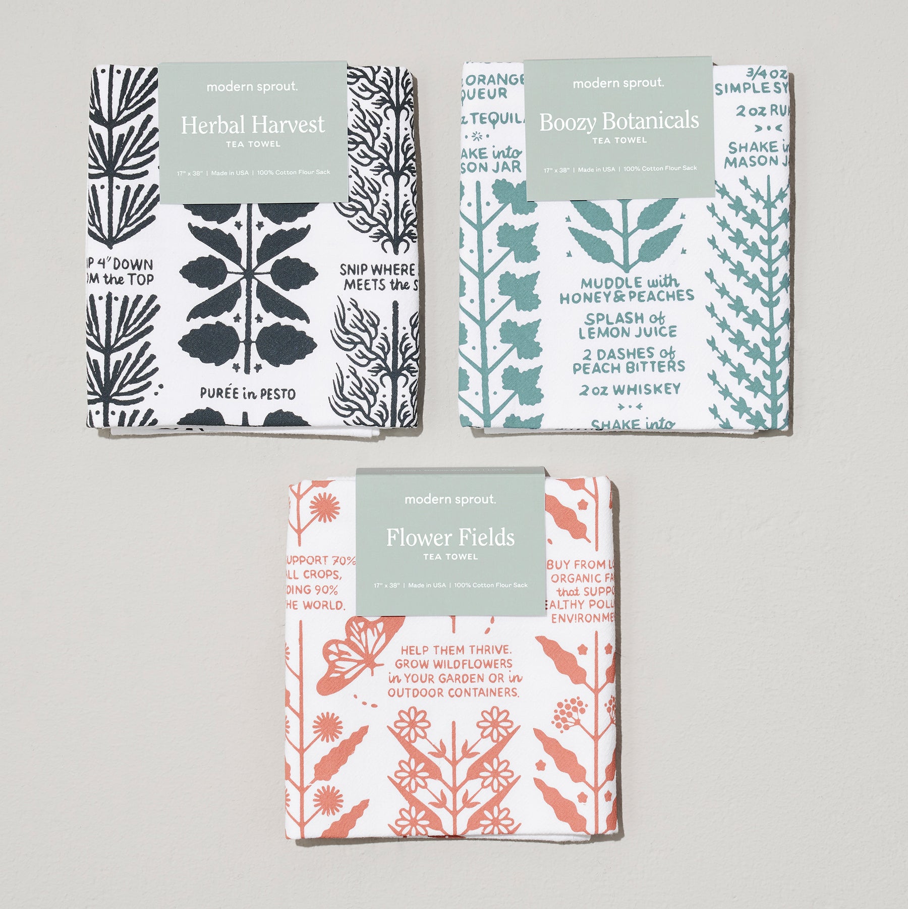 Three tea towels featuring botanical designs: "Herbal Harvest," "Boozy Botanicals," and "Flower Fields" by Modern Sprout.