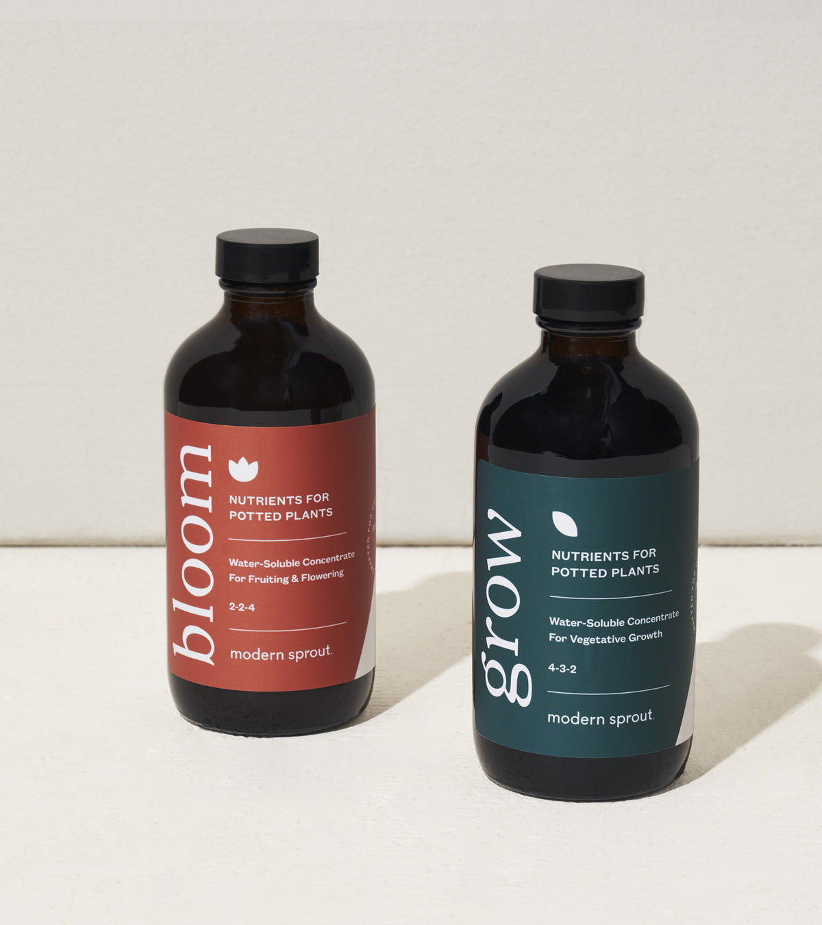 Two bottles of Modern Sprout plant nutrients for potted plants, labeled "bloom" and "grow," showcasing their water-soluble formulas.