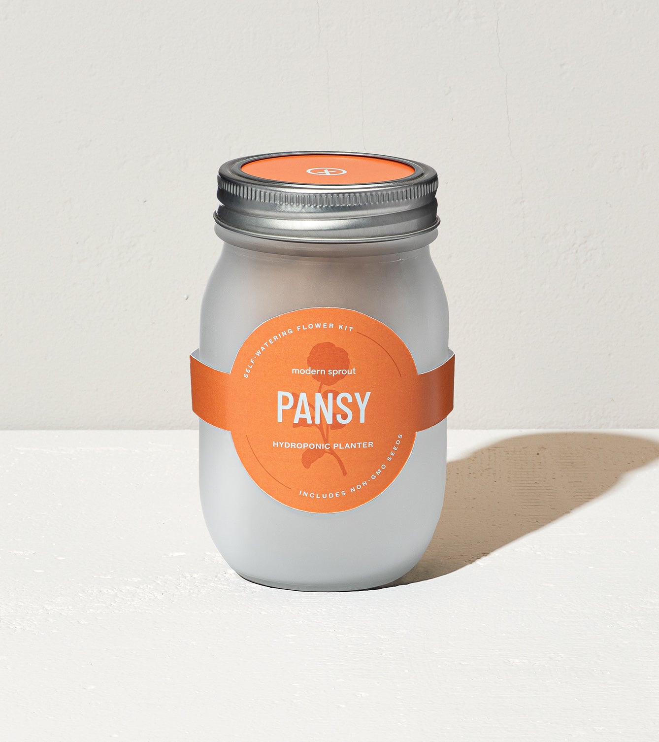 Frosted glass jar labeled "Pansy" for hydroponic planting, featuring an orange band and silver lid.